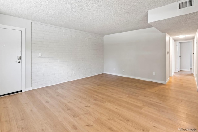 6800 E Tennessee Ave Unit 541, Denver, CO 80224 - empty room featuring a textured ceiling, brick wall, light wood-style flooring, and baseboards
