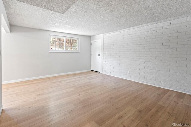 6800 E Tennessee Ave Unit 541, Denver, CO 80224 - empty room with light wood-type flooring, baseboards, brick wall, and a textured ceiling