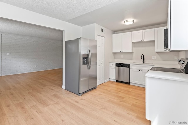 6800 E Tennessee Ave Unit 541, Denver, CO 80224 - kitchen with appliances with stainless steel finishes, brick wall, light wood-type flooring, white cabinets, and a sink