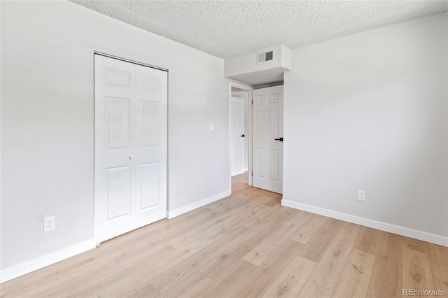 6800 E Tennessee Ave Unit 541, Denver, CO 80224 - unfurnished bedroom featuring light wood-style floors, baseboards, a closet, and a textured ceiling