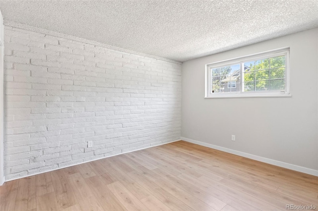 6800 E Tennessee Ave Unit 541, Denver, CO 80224 - unfurnished room featuring a textured ceiling, baseboards, light wood-style flooring, and brick wall