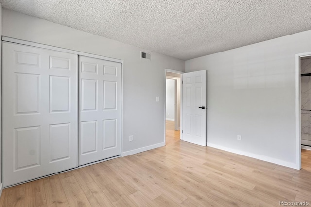 6800 E Tennessee Ave Unit 541, Denver, CO 80224 - unfurnished bedroom with light wood finished floors, a textured ceiling, a closet, baseboards, and ensuite bathroom