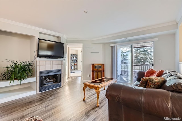 living area featuring a fireplace, crown molding, baseboards, and wood finished floors