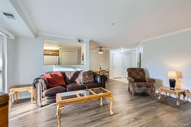 living area with ceiling fan, wood finished floors, visible vents, and crown molding