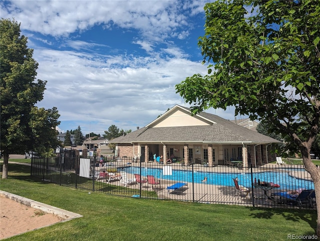 community pool featuring a patio, a lawn, and fence