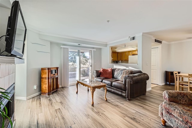 living room with light wood-type flooring, visible vents, and crown molding