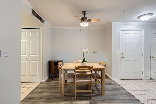 dining space with baseboards, visible vents, light wood-style flooring, ceiling fan, and crown molding