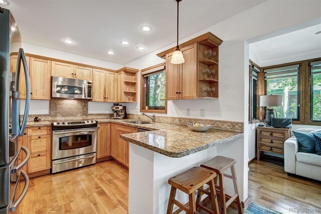 180 Nottingham Rd Unit C, Avon, CO 81620 - kitchen with stainless steel appliances, open shelves, a peninsula, light wood-type flooring, and light stone counters