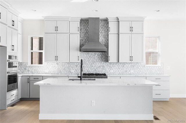 6675 Fawn Path Ln, Castle Pines, CO 80108 - kitchen featuring light wood-style floors, a sink, backsplash, and wall chimney range hood