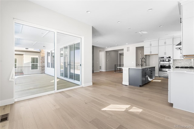 kitchen with light countertops, appliances with stainless steel finishes, white cabinetry, and open floor plan