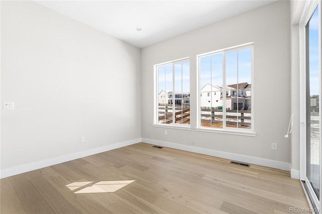 empty room featuring baseboards, visible vents, and light wood-type flooring