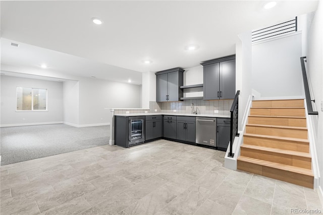 kitchen featuring decorative backsplash, a peninsula, light countertops, a sink, and dishwasher