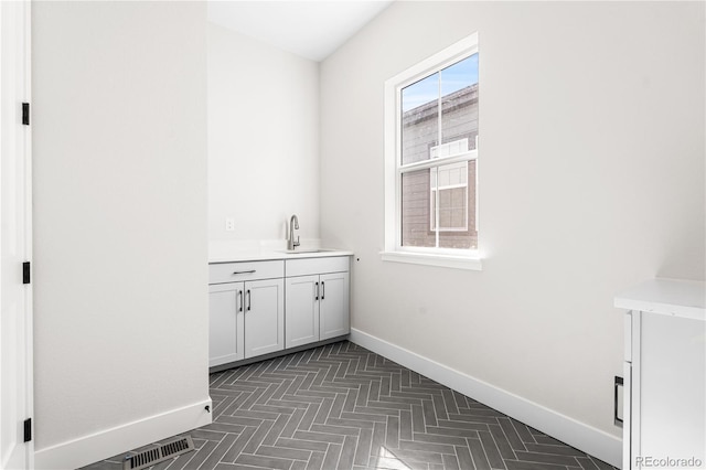 interior space featuring baseboards, visible vents, and a sink