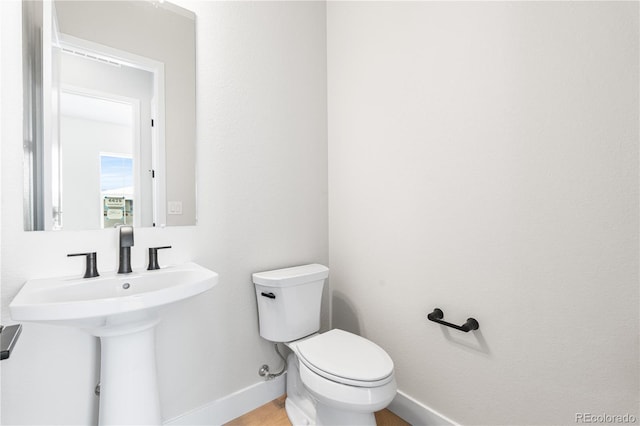 half bathroom featuring baseboards, a sink, and toilet