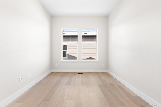 spare room featuring baseboards and light wood-type flooring