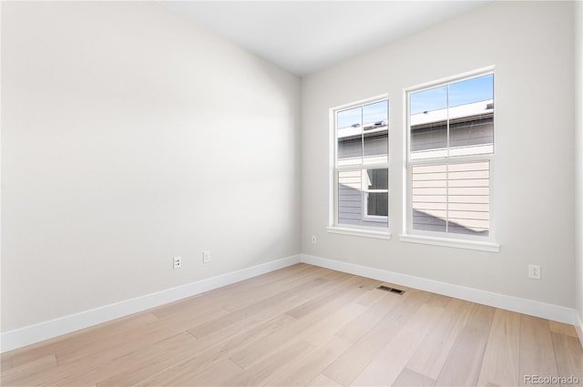 spare room with visible vents, light wood-style flooring, and baseboards