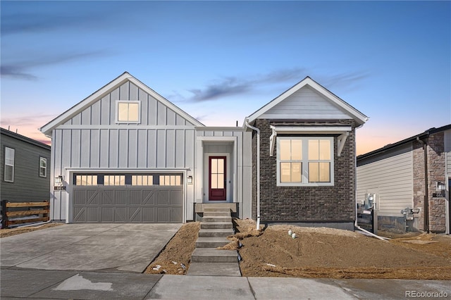 view of front facade featuring board and batten siding, an attached garage, concrete driveway, and brick siding