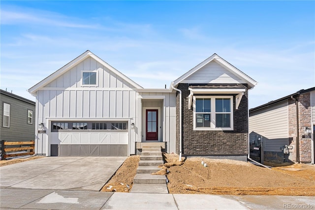 view of front of home featuring concrete driveway, brick siding, board and batten siding, and a garage