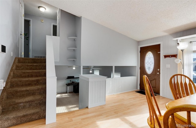 entryway with wood walls, a textured ceiling, and light wood-type flooring