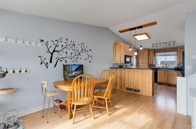 dining space with a textured ceiling, light hardwood / wood-style flooring, lofted ceiling, and sink