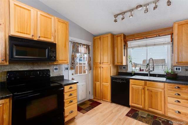 kitchen featuring light wood-type flooring, a textured ceiling, vaulted ceiling, sink, and black appliances