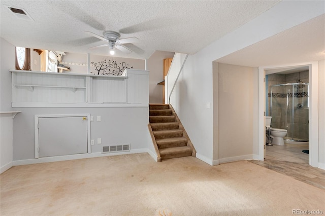 unfurnished living room featuring ceiling fan, carpet floors, and a textured ceiling