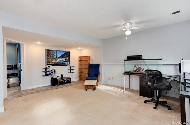 carpeted home office featuring a textured ceiling and ceiling fan