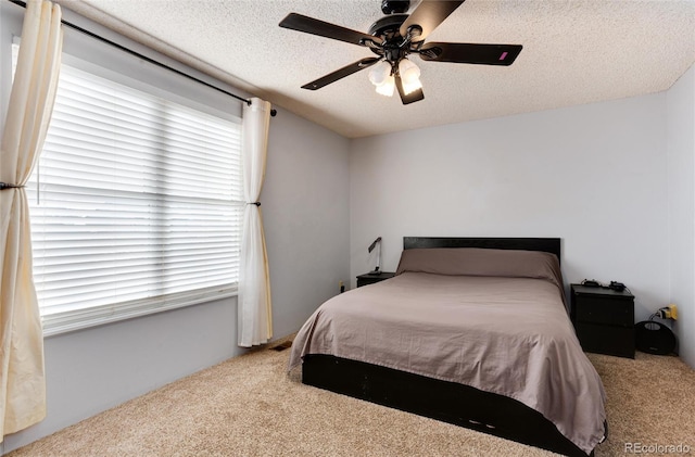 bedroom featuring multiple windows, ceiling fan, a textured ceiling, and carpet