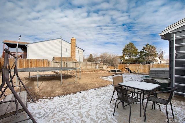 snow covered patio with a trampoline and a playground