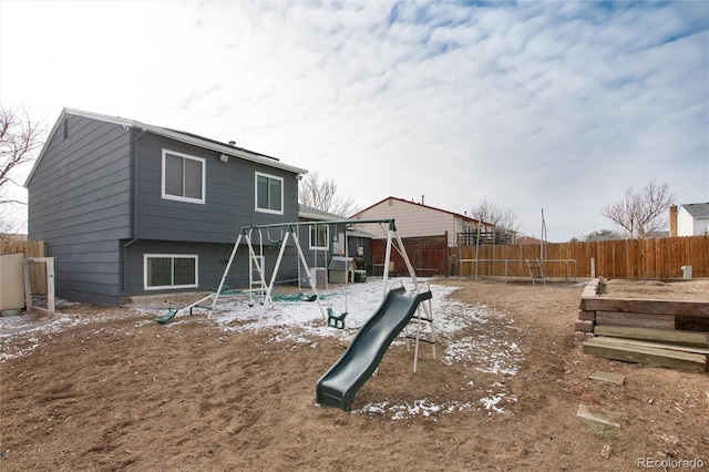 snow covered back of property featuring a playground