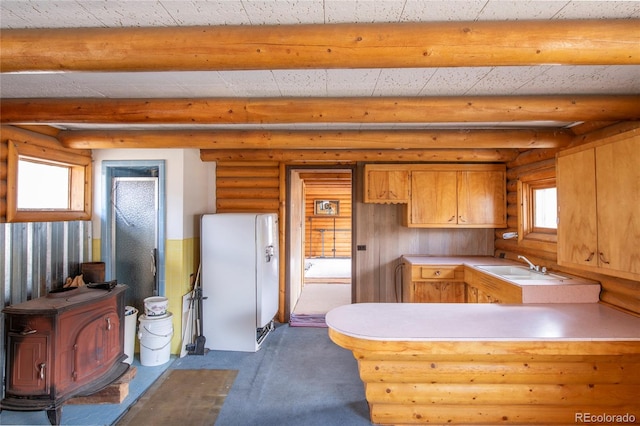 kitchen featuring a wealth of natural light, kitchen peninsula, rustic walls, and sink