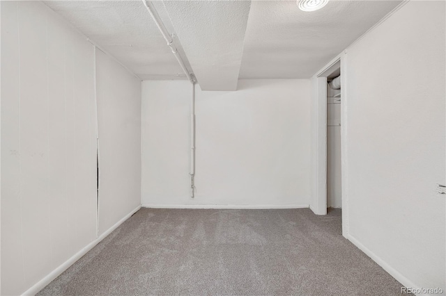 spare room featuring a textured ceiling, carpet flooring, and baseboards