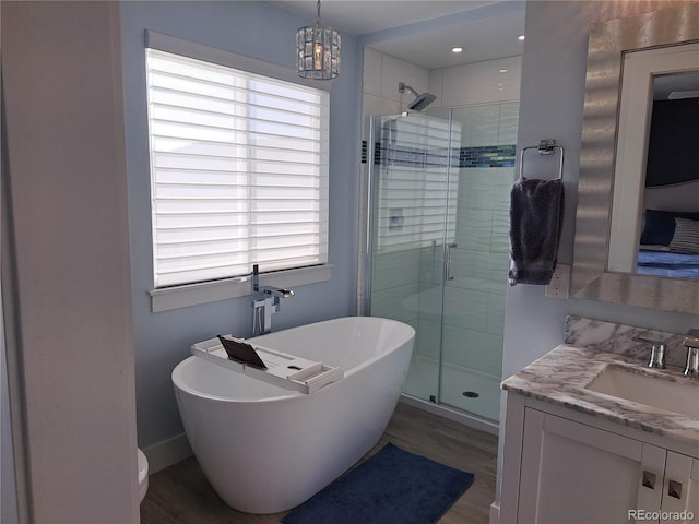 15945 Delta Ct, Brighton, CO 80603 - bathroom with a stall shower, vanity, a freestanding tub, wood finished floors, and a chandelier