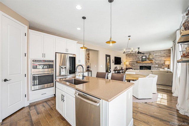 3480 Mount Powell Dr, Broomfield, CO 80023 - kitchen with dark wood-style flooring, a kitchen island with sink, a sink, decorative light fixtures, and stainless steel appliances