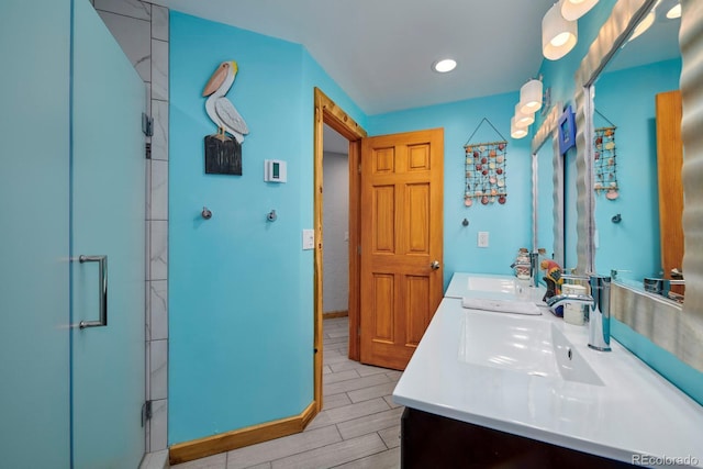 bathroom featuring wood tiled floor, a sink, a shower stall, and double vanity