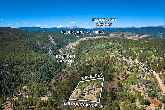 birds eye view of property featuring a mountain view and a view of trees