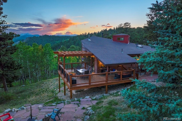 back house at dusk featuring a patio and a deck