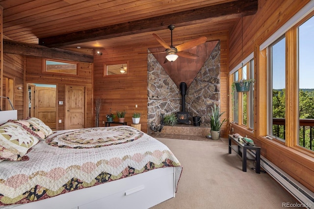 carpeted bedroom featuring wood walls, wooden ceiling, and a wood stove