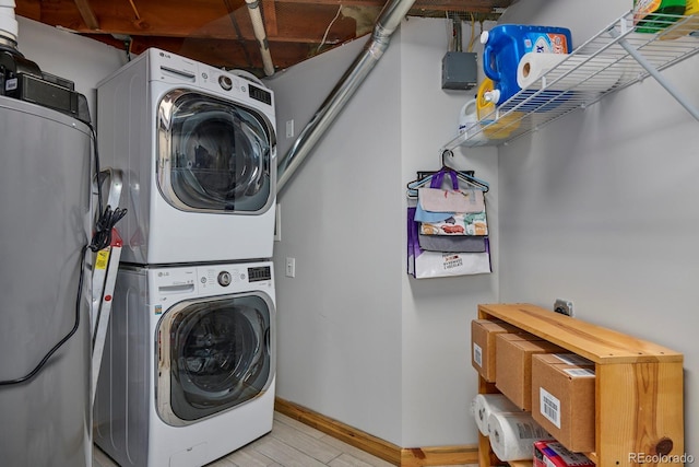 laundry area with laundry area, stacked washer / dryer, light wood-style flooring, and baseboards