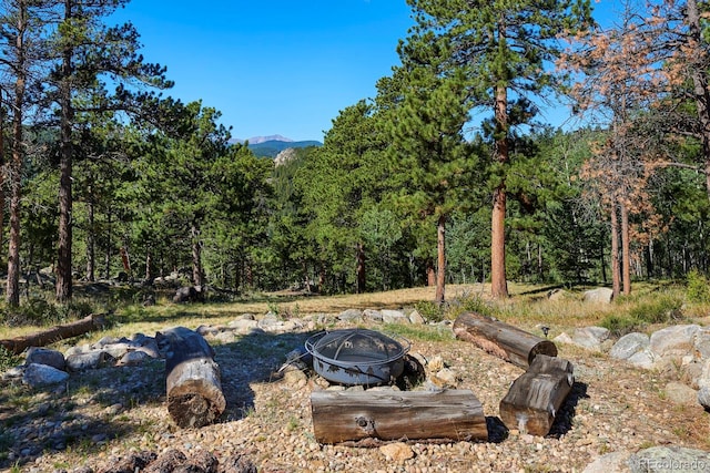 view of yard with a fire pit and a wooded view