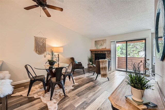 4285 S Salida Way Unit 17, Aurora, CO 80013 - dining room with a textured ceiling, wood finished floors, a stone fireplace, a ceiling fan, and baseboards