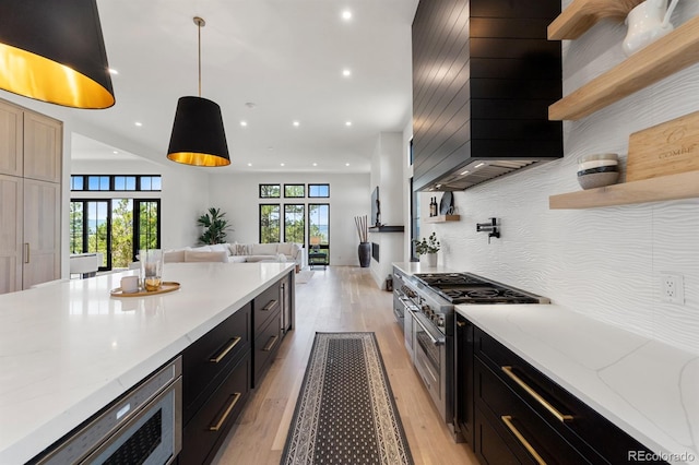 kitchen with double oven range, light stone countertops, backsplash, and decorative light fixtures