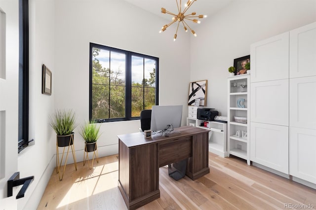 office featuring a high ceiling, a chandelier, and light wood-type flooring