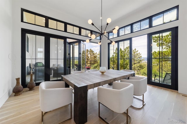 dining area featuring french doors, a chandelier, and light hardwood / wood-style floors