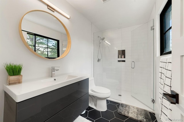 bathroom with vanity, tile patterned floors, a shower with door, and toilet