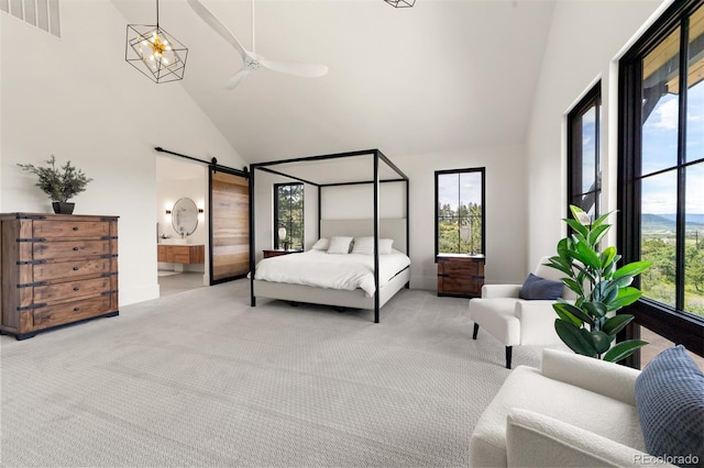 carpeted bedroom featuring ensuite bath, a barn door, and high vaulted ceiling