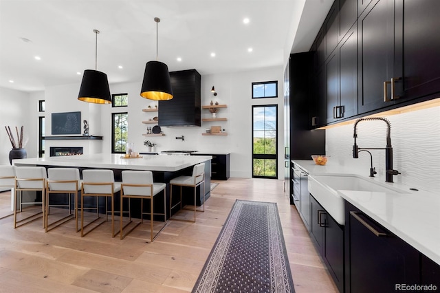 kitchen with a breakfast bar, sink, hanging light fixtures, plenty of natural light, and light hardwood / wood-style floors