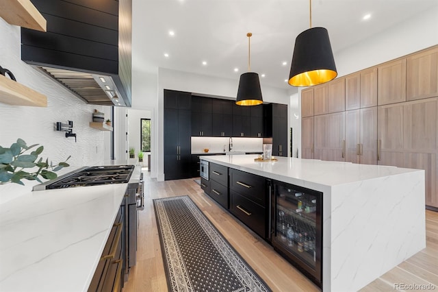 kitchen featuring a large island, pendant lighting, beverage cooler, and light hardwood / wood-style floors