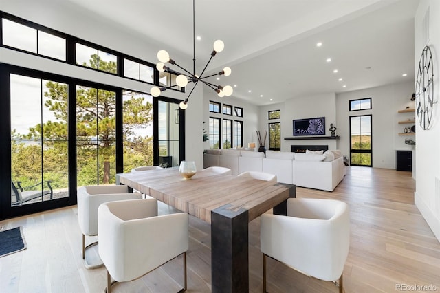 dining room with a healthy amount of sunlight, a chandelier, and light wood-type flooring