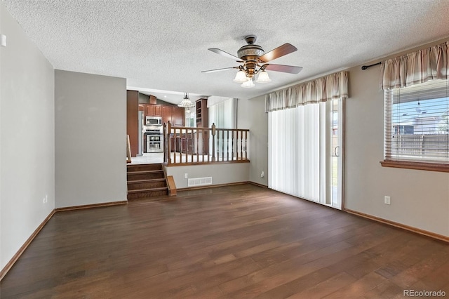 3973 S Joplin Way, Aurora, CO 80013 - unfurnished living room with dark wood-style flooring, ceiling fan, a textured ceiling, and stairs